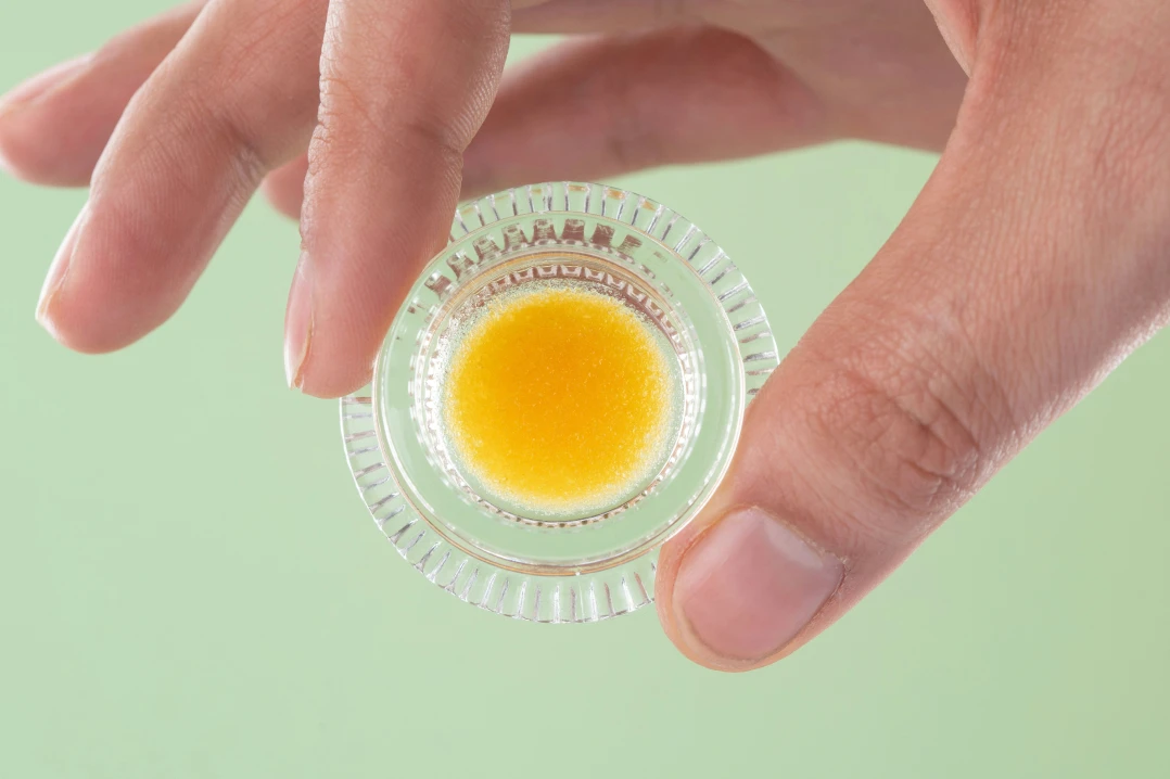 someone holding a glass container of THCA concentrate